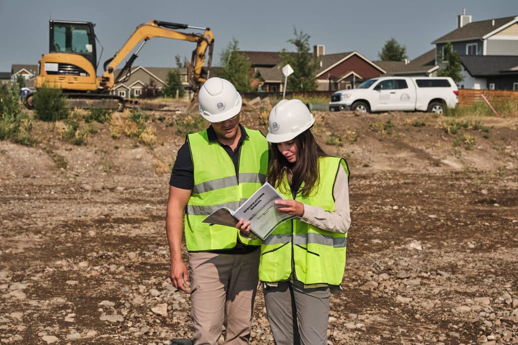 Allied Engineering team members planning at a subdivision project with excavation equipment in the background.